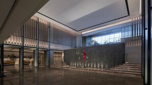 A spacious lobby with a modern design, featuring a large staircase, a reception desk, and a unique sculpture.