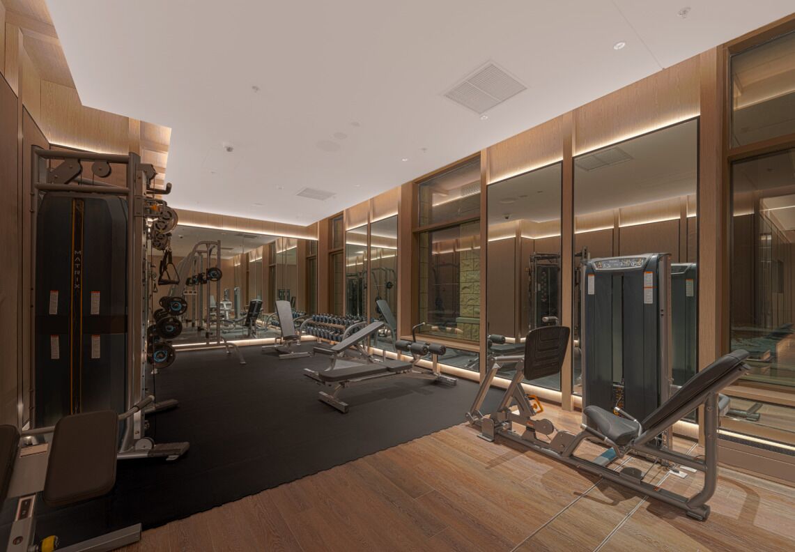 Un gimnasio moderno con diverso equipo de ejercicio, espejos amplios y suelo de madera.