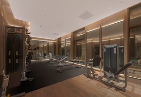 Un gimnasio moderno con diverso equipo de ejercicio, espejos amplios y suelo de madera.