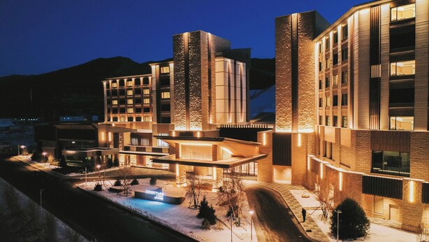 A modern hotel with multiple buildings, a courtyard, and a pool area.