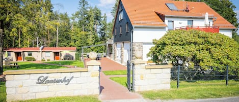 Une maison à deux étages, avec un toit recouvert de tuiles rouges, un portail d’entrée en pierre et une enseigne indiquant « Laasenkof ».
