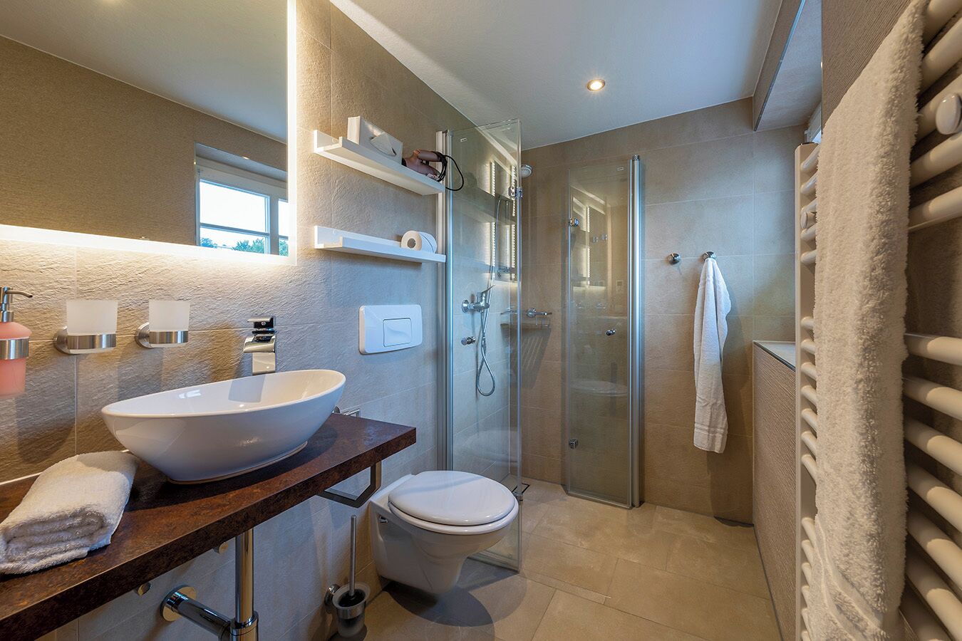 A modern bathroom with a freestanding sink, toilet, and walk-in shower.