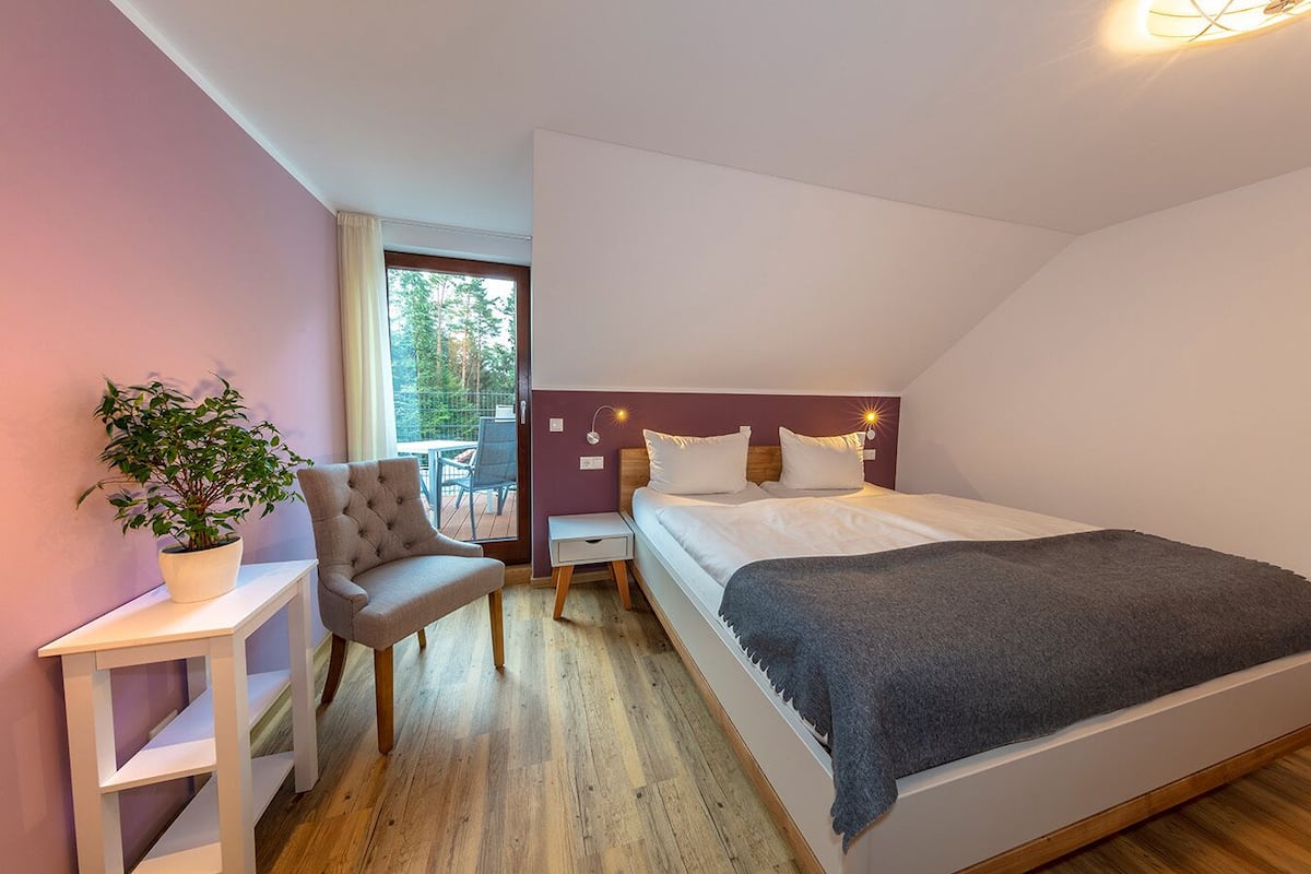 Une chambre moderne avec un lit, une chaise, une petite table et une plante en pot.