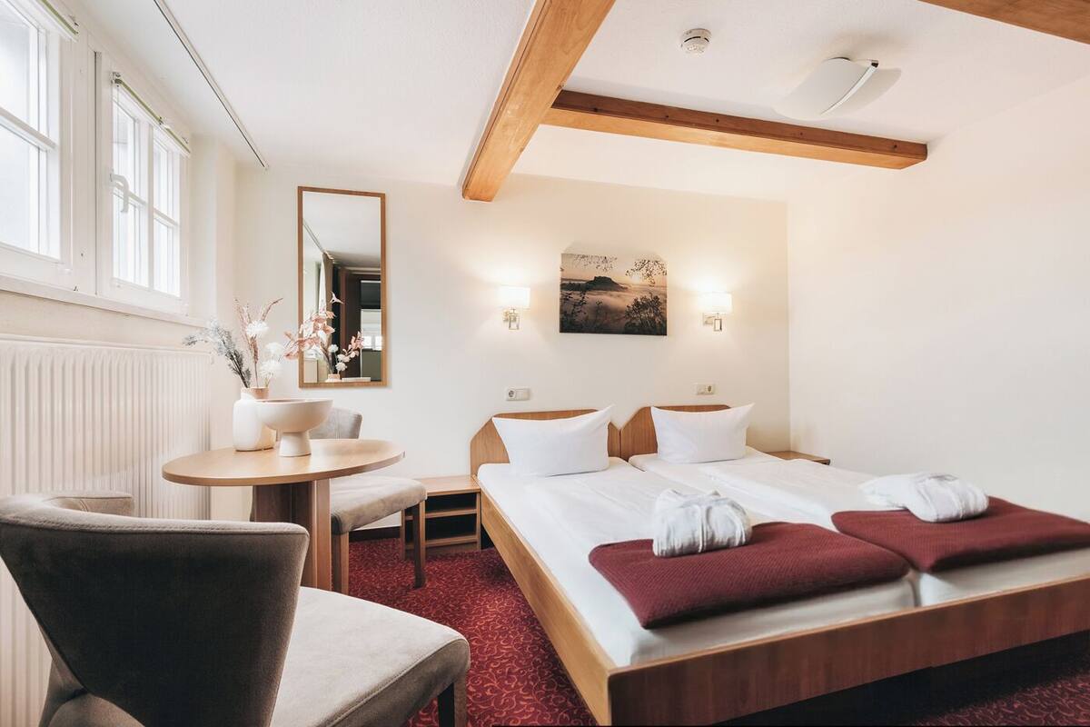 Une chambre d’hôtel comprenant un lit, un bureau, une chaise, une table ronde et un miroir.