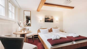 Una camera d'albergo con un letto, una scrivania, una sedia, un tavolo rotondo e uno specchio.