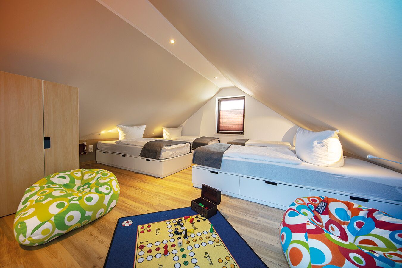 A bedroom with two beds, a wardrobe, and a window.