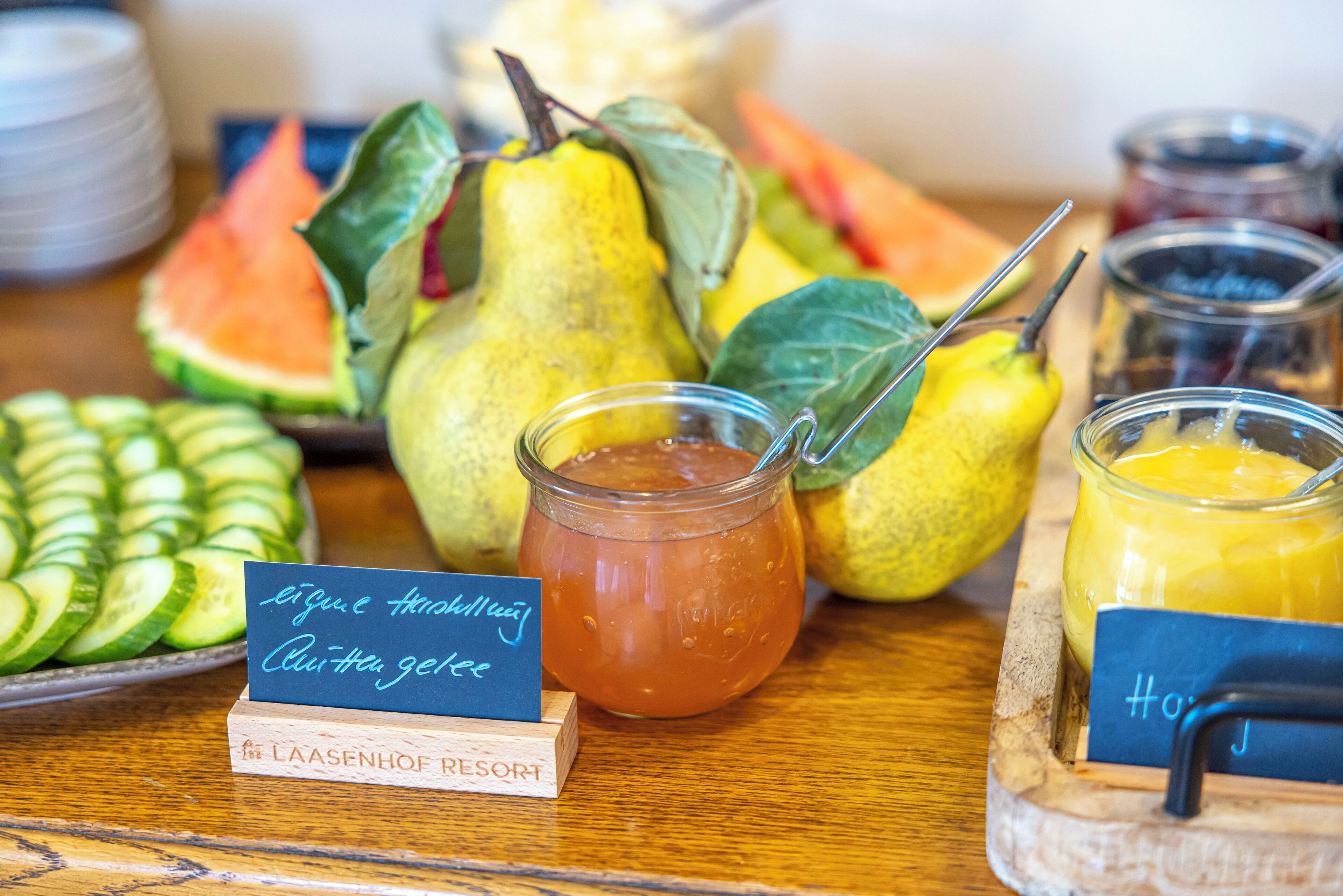 Ein Buffet mit verschiedenen Früchten, einem Einmachglas und einem Schild mit dem Namen des Hotels.