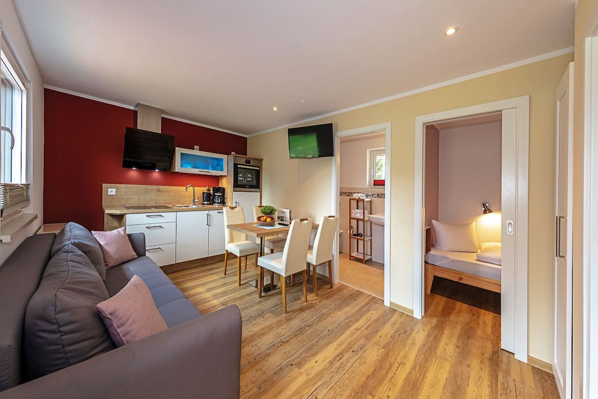 Un espace de vie compact comprenant une kitchenette, un coin repas et une chambre.