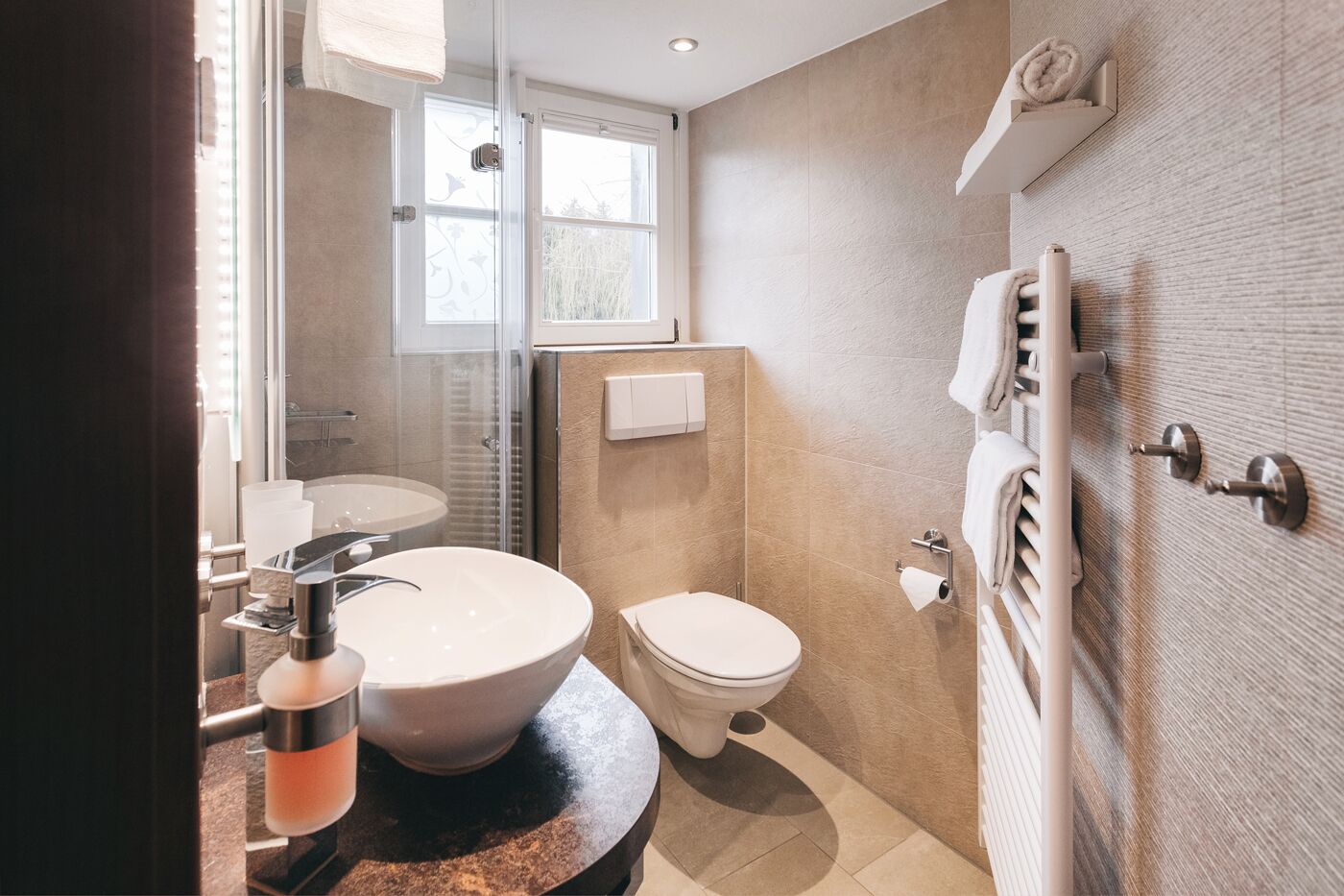 Een moderne badkamer met een groot wastafel, toilet en douche.