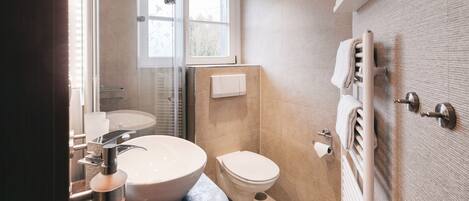 Een moderne badkamer met een groot wastafel, toilet en douche.