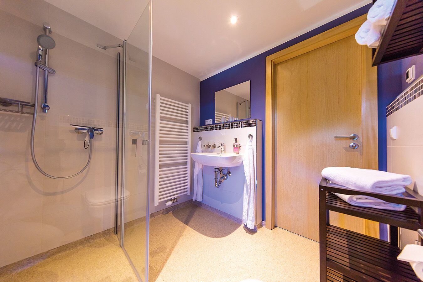 Un baño moderno con cabina de ducha de vidrio, un lavabo con espejo y una puerta de madera.