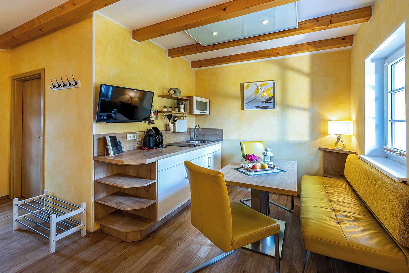 A compact living space with a kitchenette, a dining area, and a seating area with a sofa and a chair.