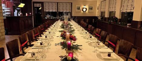 Una larga mesa de comedor vestida con manteles blancos, velas y adornos navideños.