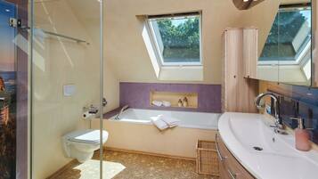 A modern bathroom with a glass shower enclosure, a freestanding bathtub, and a vanity with a large mirror.
