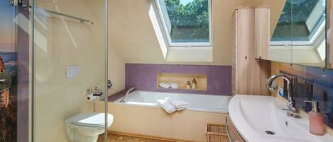 A modern bathroom with a glass shower enclosure, a freestanding bathtub, and a vanity with a large mirror.