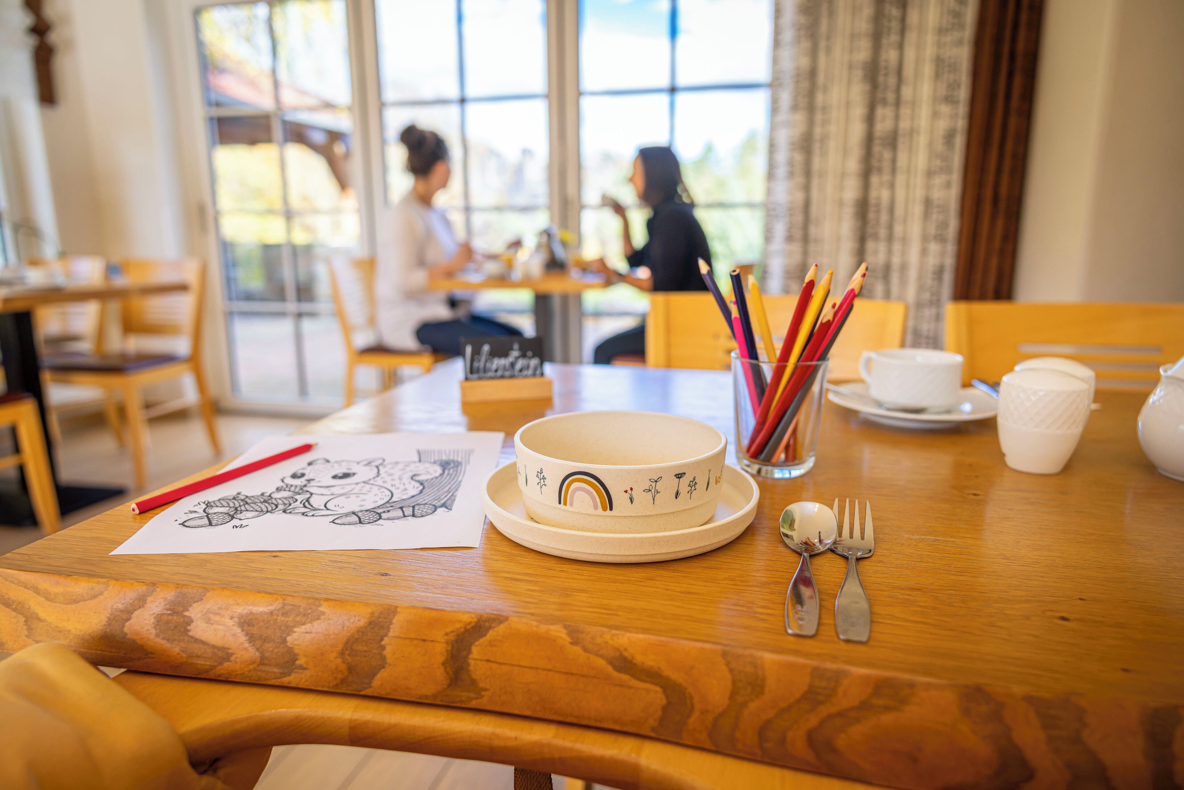A dining table with a bowl, utensils, and a drawing.