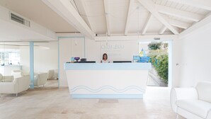 A reception area with a modern design, featuring a reception desk, seating area, and a view of the outdoors. - Oasi Blu Sardinia (Pula)