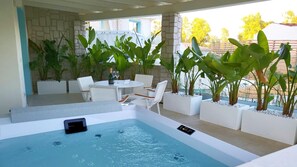 A modern outdoor pool area with a hot tub, white lounge chairs, and potted plants. - Oasi Blu Sardinia (Pula)