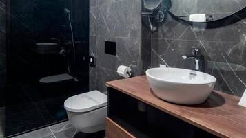 A modern bathroom with a white toilet, a large mirror, and a wooden vanity with a white sink.
