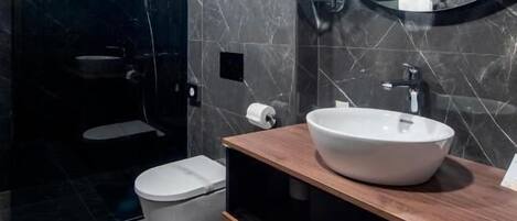 Un baño moderno con inodoro blanco, un espejo grande y un mueble de tocador de madera con lavamanos blanco.