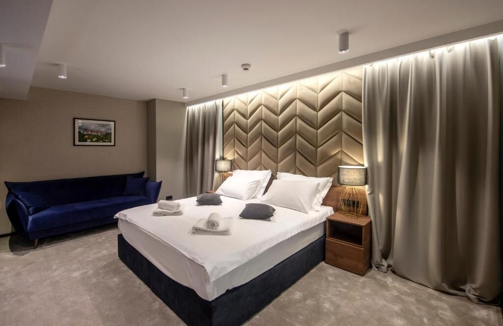 Ein modernes Hotelzimmer mit einem großen Bett, einem blauen Sofa und einem dekorativen Kopfteil.
