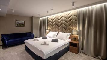 Ein modernes Hotelzimmer mit einem großen Bett, einem blauen Sofa und einem dekorativen Kopfteil.