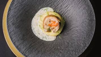 A round, dark slate plate with a golden rim, containing a food item garnished with green herbs.
