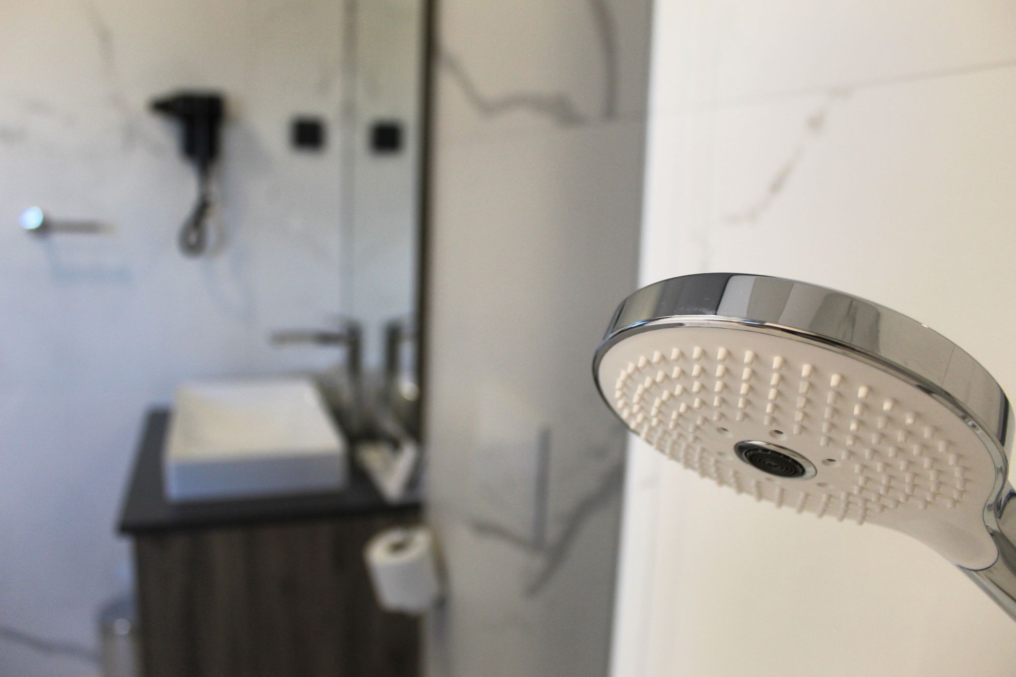 A bathroom with a shower head, a sink, and a toilet.