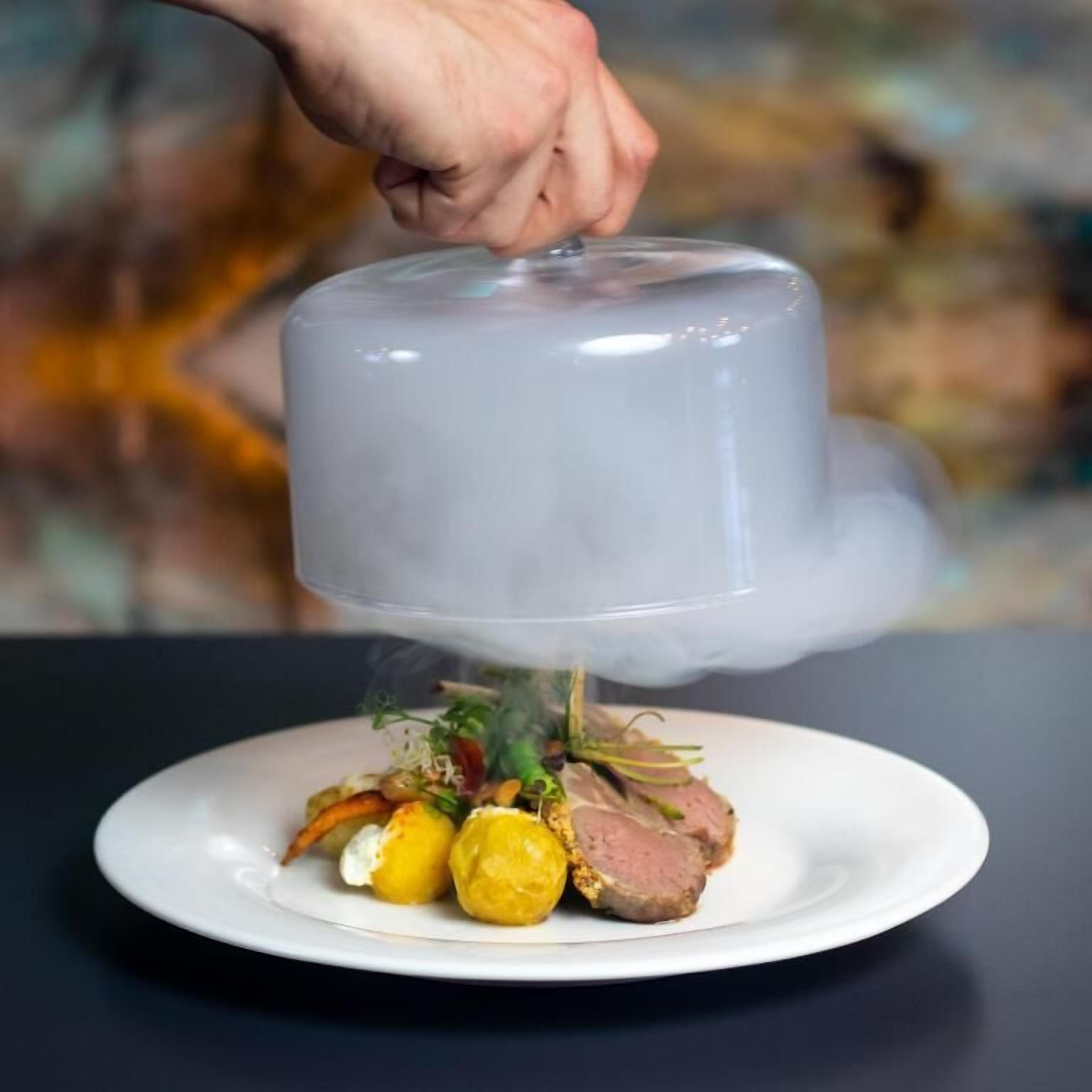 Un plato con comida y una mano sosteniendo un objeto transparente encima.