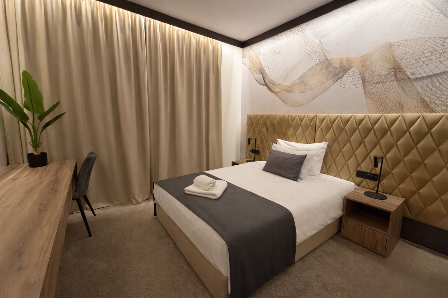 Una habitación de hotel moderna con una cama grande, un escritorio y una planta en maceta.