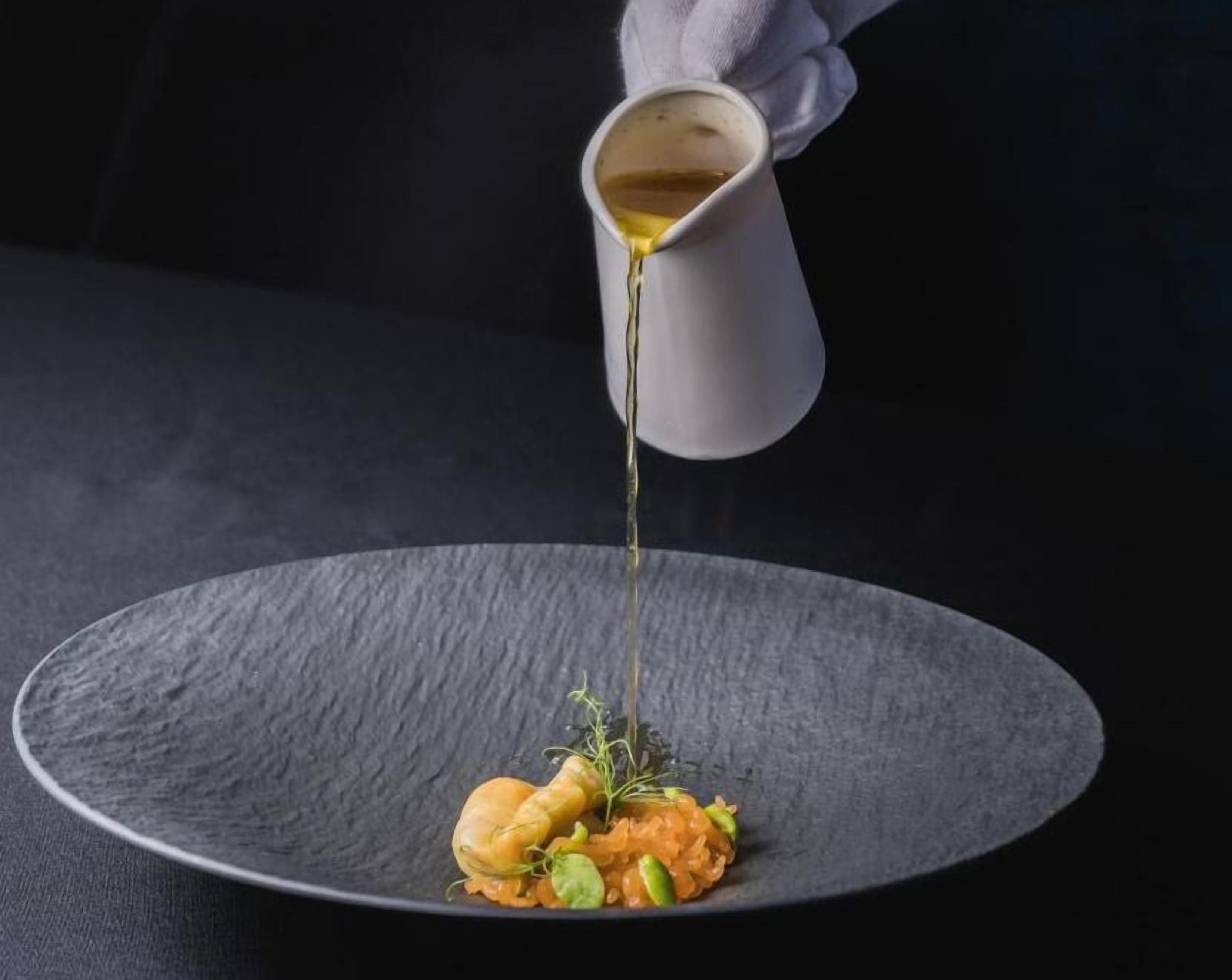 A dish with a sauce being poured onto it.