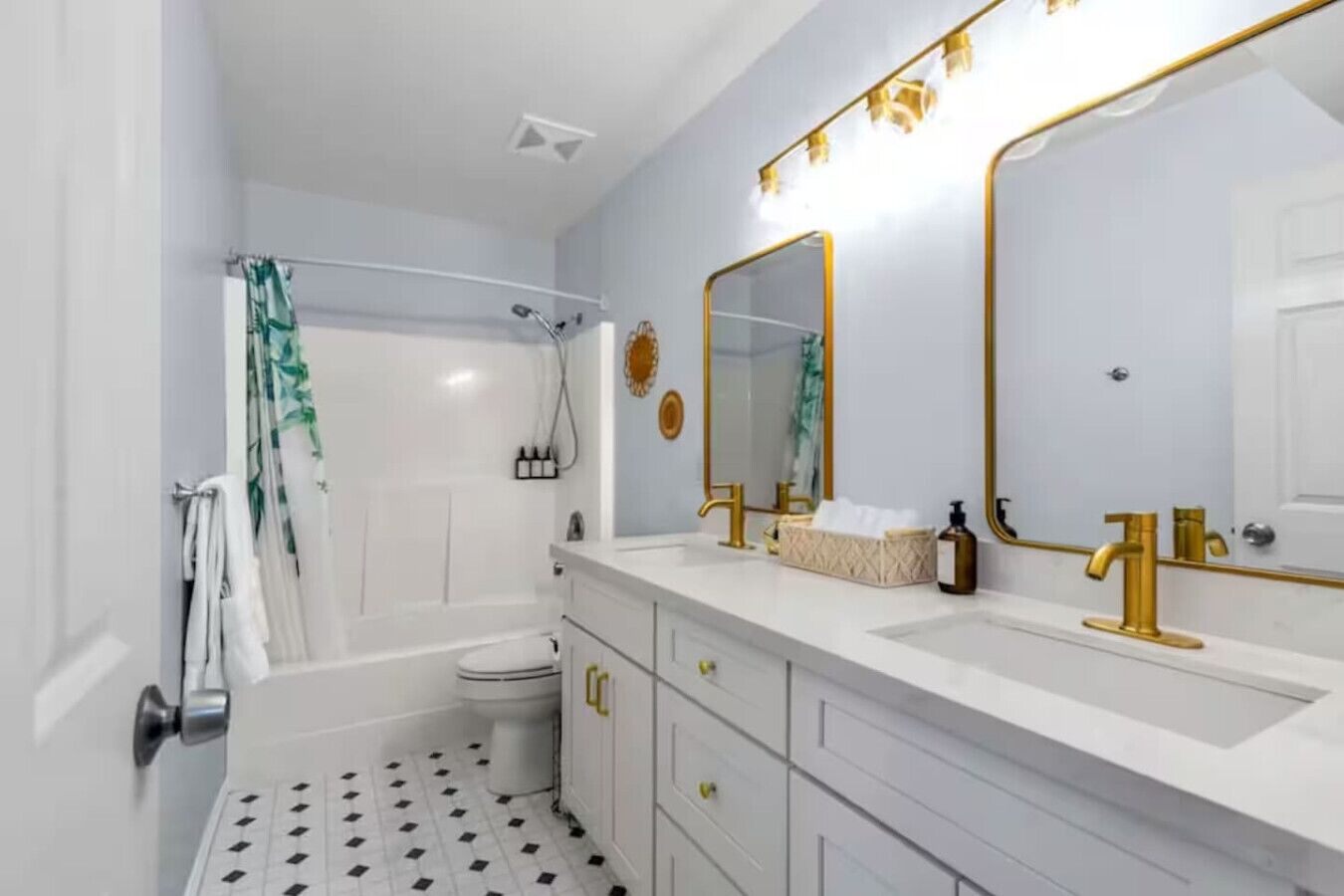 Ein Badezimmer mit Badewanne, Toilette und zwei Waschbecken mit goldenen Wasserhähnen.