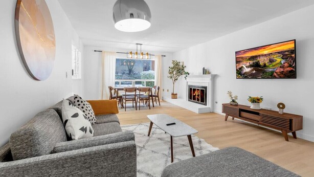 Ein modernes Wohnzimmer mit Kamin, einem Essbereich mit Tageslicht und einem großen Fenster.