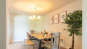 A dining area with a wooden table, four chairs, a bench, a chandelier, framed artwork on the wall, and a potted plant. - 9852 Upper · 4b2b Upper Unit @S Seattle w/ Panoramic Lake View (Seattle)