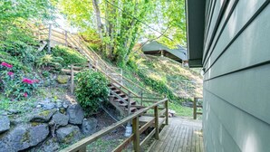 A wooden staircase leading to a covered area with a view of a garden and a building. - 9852 Upper · 4b2b Upper Unit @S Seattle w/ Panoramic Lake View (Seattle)