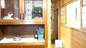 A wooden interior with a clock, a Christmas tree, and a cabinet with a plant. - Chatan Beach House 1 (Chatan)