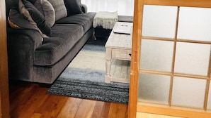 A living room with a dark grey sofa, a wooden coffee table, and a patterned rug. - Chatan Beach House 1 (Chatan)