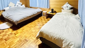 A hotel room with two beds, wooden flooring, a small table, and an air conditioning unit. - Chatan Beach House 1 (Chatan)