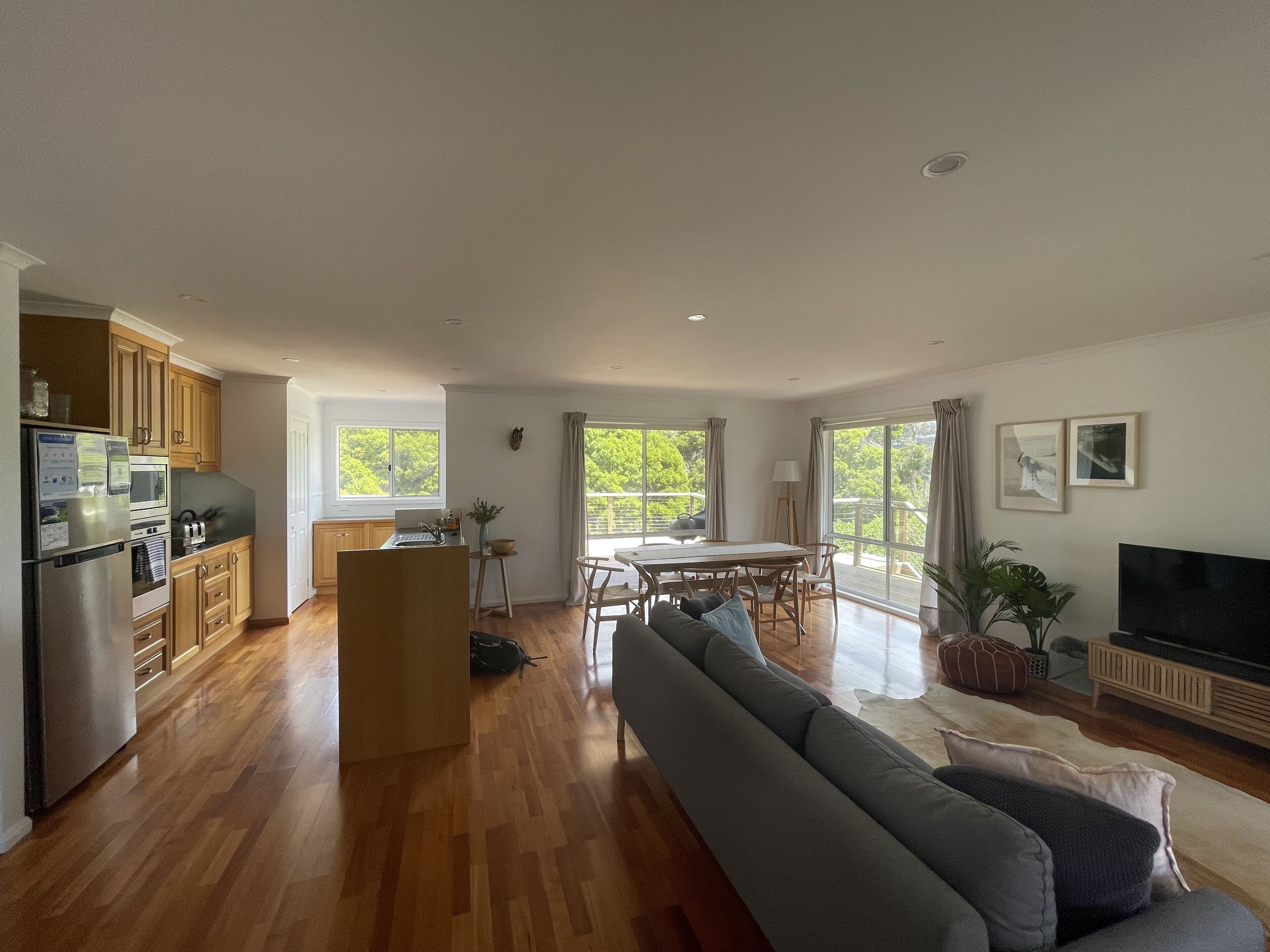 A spacious living area with a sofa, dining table, and kitchen area with wooden cabinets and appliances.
