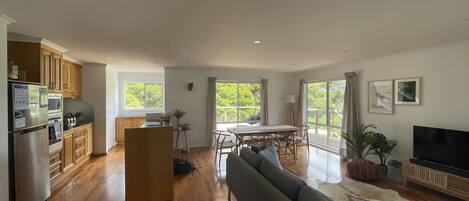 A spacious living area with a sofa, dining table, and kitchen area with wooden cabinets and appliances.