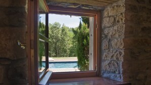 A stone-walled room with a window overlooking a swimming pool and greenery. - Charming & Authentic Stone House La Brugna (Baselica, frazione di Borgo Val Di Taro)