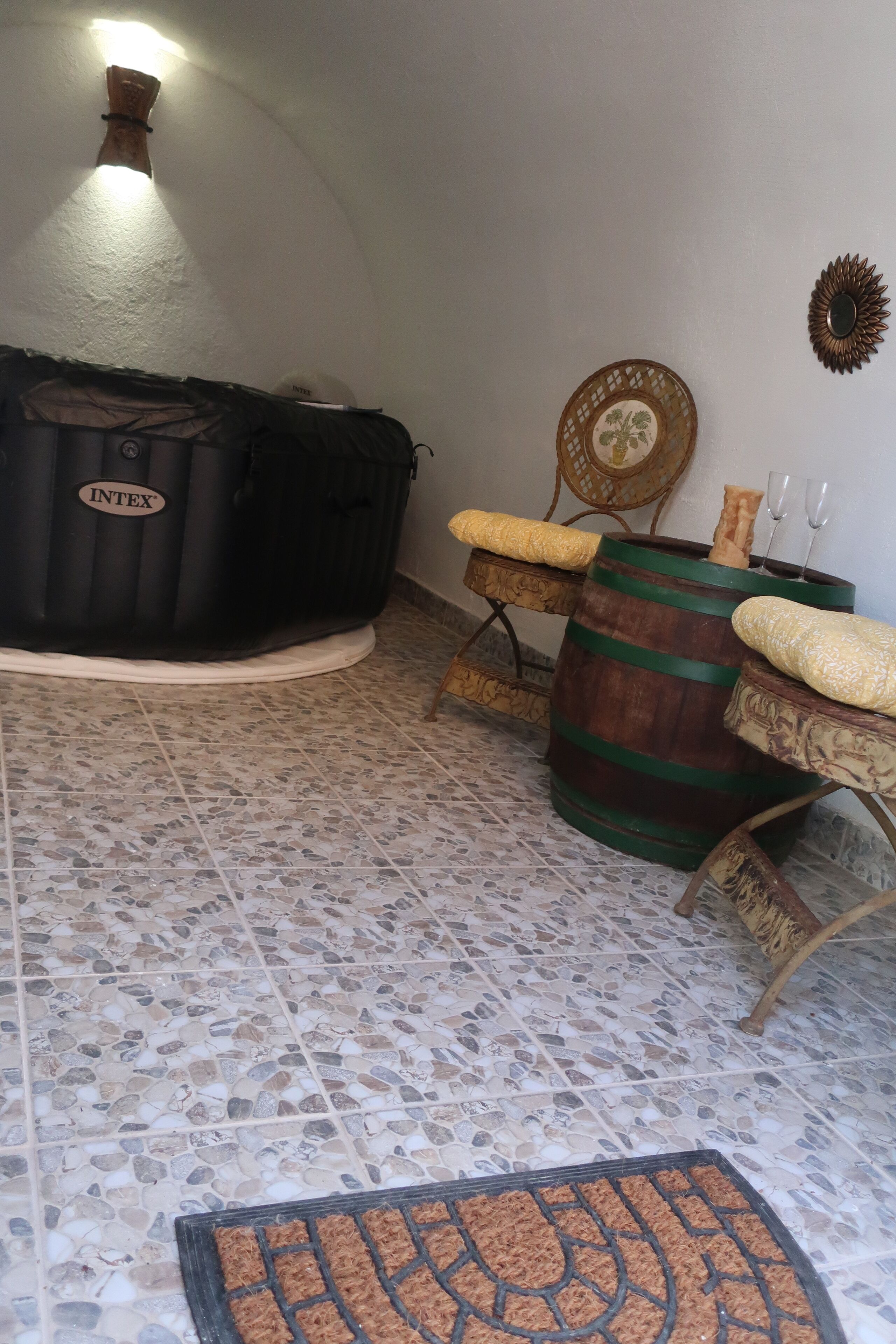 Ein Zimmer mit Whirlpool, Holzfass und einem Stuhl mit Flechtwerk-Sitz.
