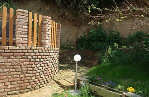 A brick wall with a wooden fence, a spherical light post, and a garden with various plants and flowers.