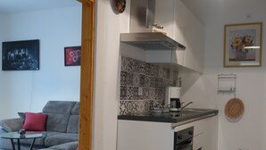 A compact kitchen with a gas stove, oven, and a small stool. A grey sofa with red cushions is in the adjacent living area. - Year-round holiday home with swimming pool and whirlpool. Dogs welcome! (Döbrököz)