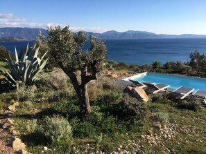 A pool with a view of the sea and mountains.