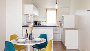 Une cuisine de taille réduite avec des meubles blancs, un plan de travail en bois et une fenêtre au-dessus de l’évier.