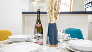 Une table à manger dressée avec de l’assiette blanche, des verres et une bouteille de cidre brut de Bretagne.