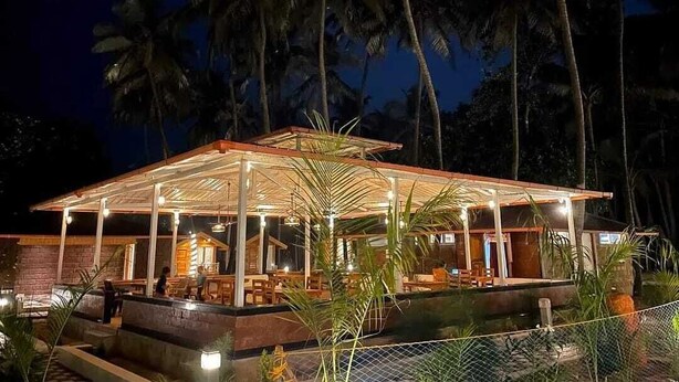 Un espacio al aire libre cubierto con asientos y una piscina, rodeado de palmeras.