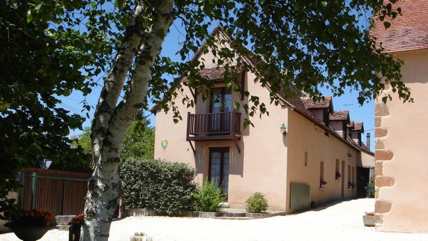 Un bâtiment à deux étages doté d’un balcon, d’une allée en gravier et d’un petit jardin.