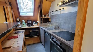 Eine kompakte Küche mit Fenster, Einbaugeräten und einem kleinen Spülbecken.